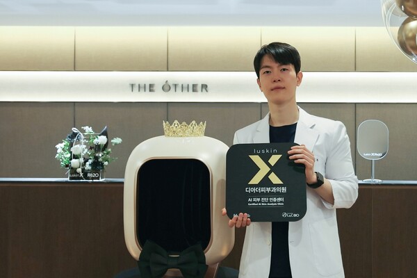 흰 가운을 입은 이승주 원장이 병원 로비에서 루스킨엑스 현판을 들고 서 있다